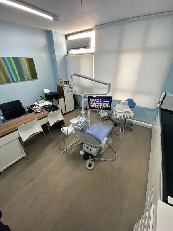 Fotografia de sala de espera de consultório odontológico com três cadeiras brancas.